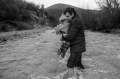 Un uomo porta in braccio il figlio mentre tenta di attraversare il confine con la Macedonia. Macedonia, 2016,  James Nachtwey